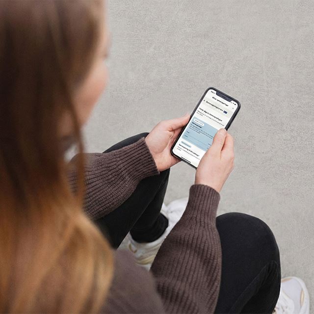 Kvinna hyggur eftir samansparingum í netbankanum á mobiltelefonini