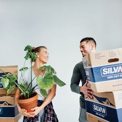 Ungt par med flyttekasser og en plante