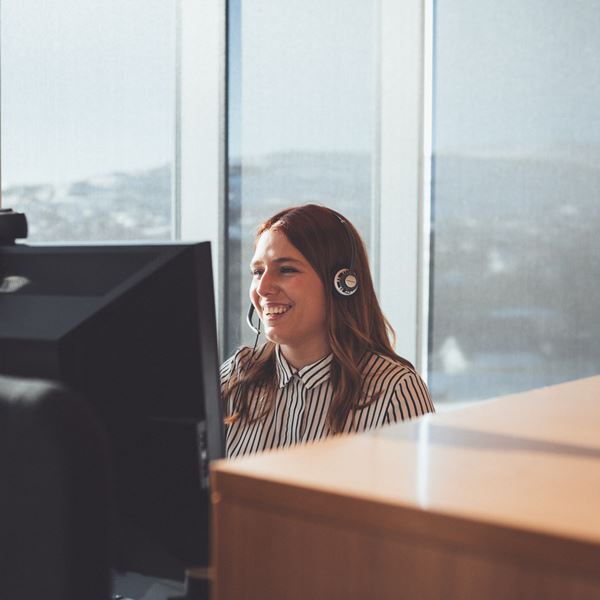 Kvinde ved computer på kontor med headset