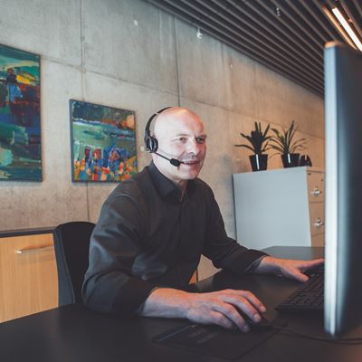 Mand ved computer på kontor med headset
