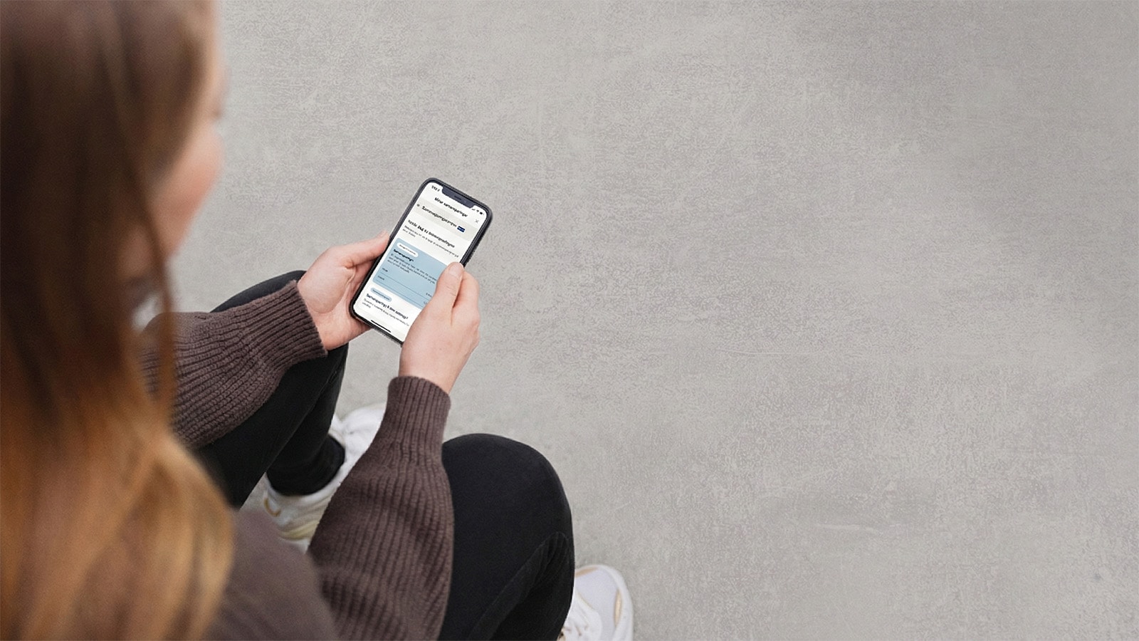 Kvinna hyggur eftir samansparingum í netbankanum á mobiltelefonini