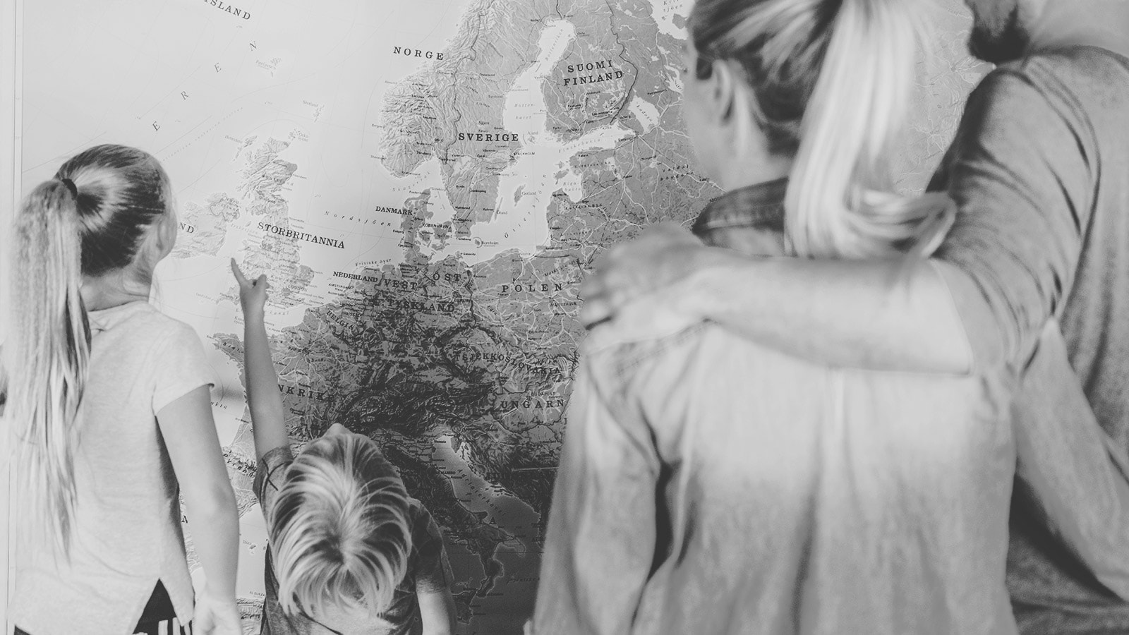 Familie, der står og kigger på et verdenskort