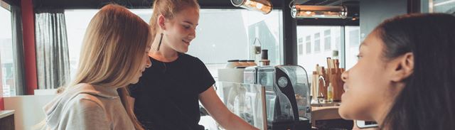 Tre teenagepiger betaler i en café