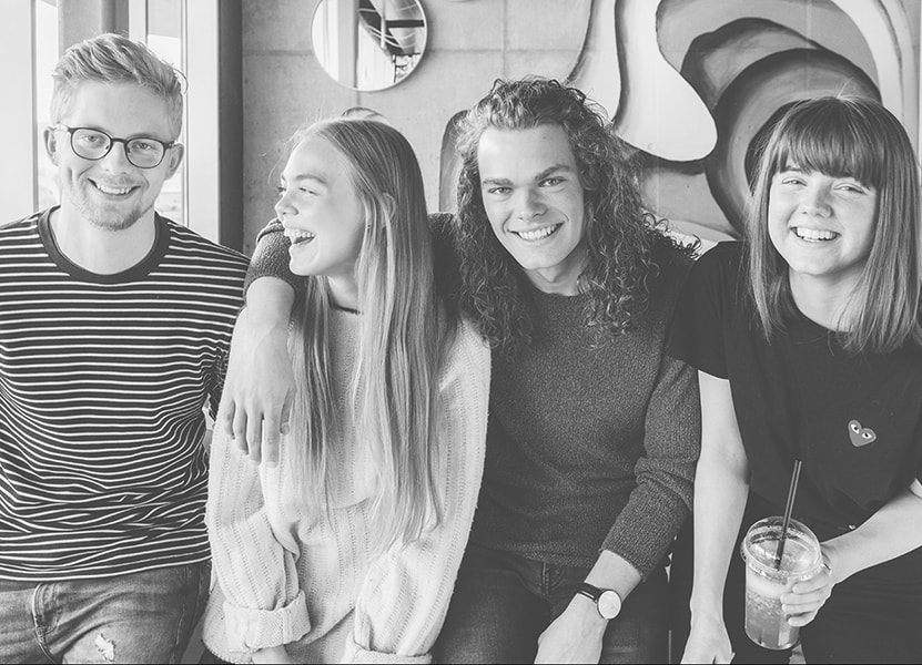 Fire unge mennesker, der hygger sig på cafe
