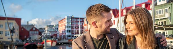 Par situr og drekkur kaffi við bátahylin