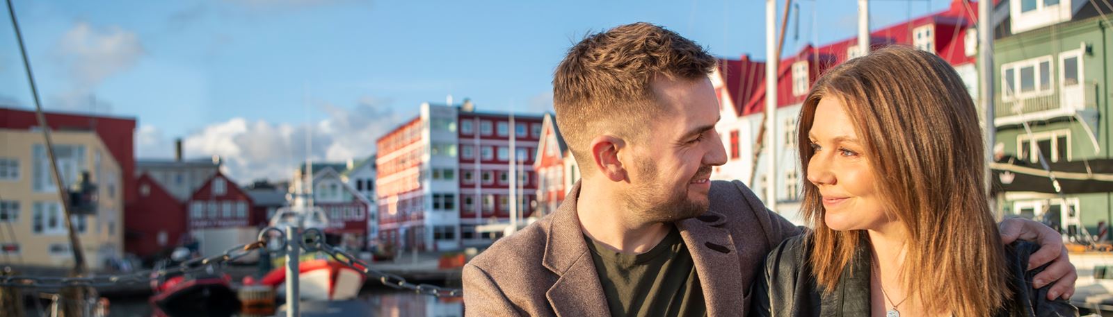 Par situr og drekkur kaffi við bátahylin